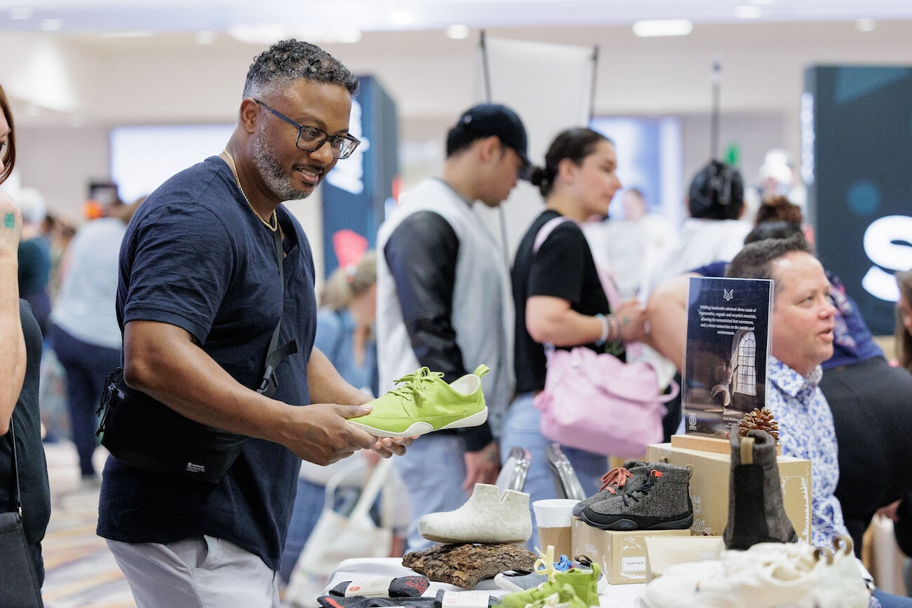 A visitor examining a bright green barefoot trainer, photo by Barefoot Shoe Expo