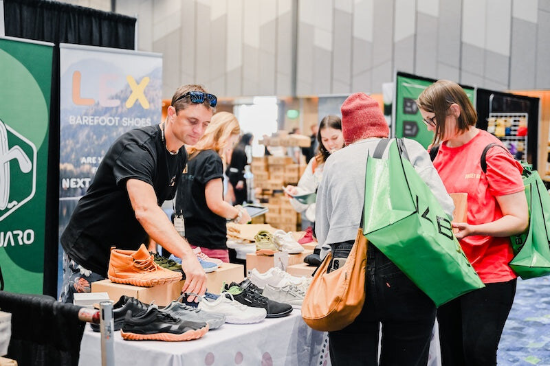 An exhibitor discussing barefoot shoes with visitors, photo by Barefoot Shoe Expo