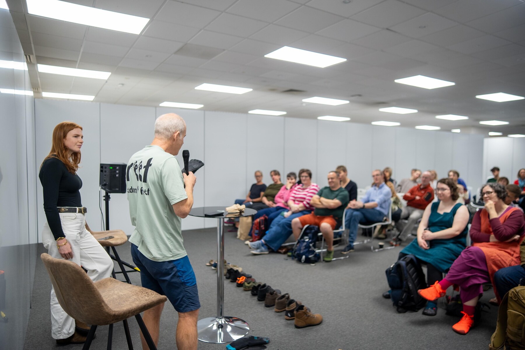 A speaker presenting to a seated audience at a foot health talk, photo by Barefoot Brit Expo